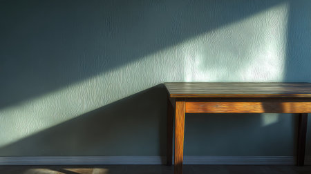 This image showcases a minimalist room interior featuring a wooden table casting long shadows against a textured wall in soft natural light.の素材