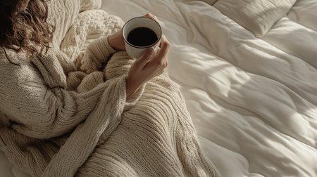 A serene image capturing a person in a soft blanket, holding a warm cup of coffee, embodying comfort and relaxation in a cozy home setting.の素材