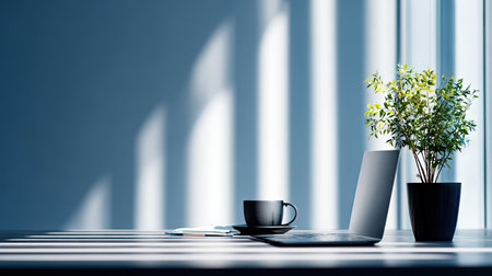 A serene modern workspace featuring a laptop, a coffee cup, and a small potted plant, illuminated by bright sunlight and soft shadows. Perfect for inspiring focus.の素材