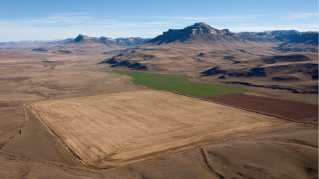 Stunning aerial view showcasing a vast dry landscape with patches of farmland contrasted against majestic mountain peaks, reflecting the beauty of nature.の素材