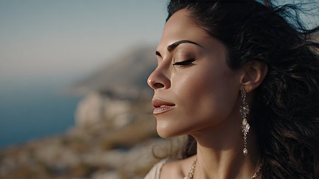 A beautiful woman enjoys a moment of tranquility, with flowing hair and elegant earrings, set against a breathtaking ocean view, embodying peace and serenity.の素材