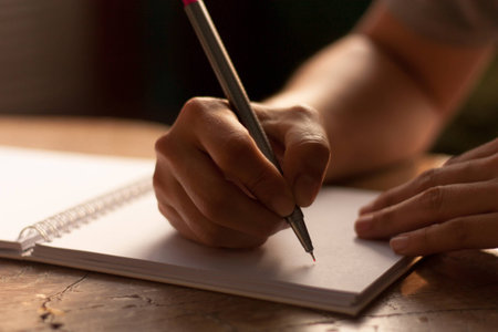 Human hand with the pen writing on the notebook that align on the wooden table.の写真素材