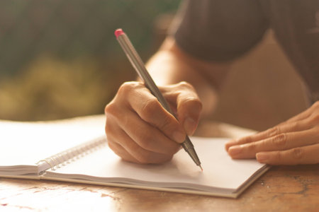 Human hand with the pen wirting on the notebook that align over the wooden table with blurry backgroundの写真素材