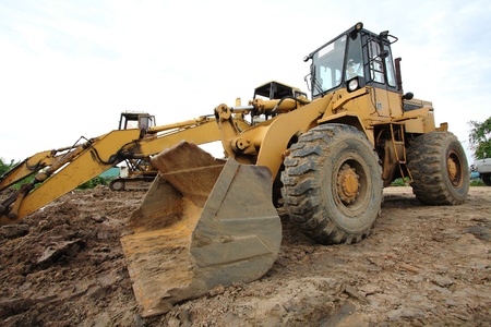 loader Excavator with backhoe unloading sand at earthmoving works in construction site