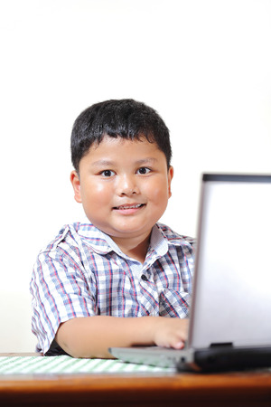 Asian boy was playing with my notebook.の写真素材