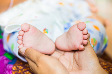 Baby feet cupped into mothers hands.の写真素材