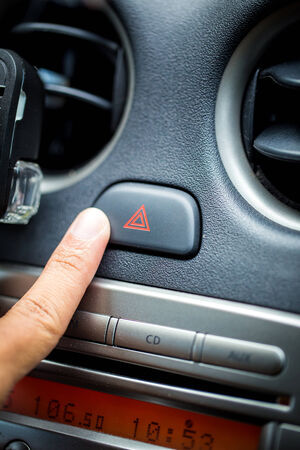 transportation and vehicle concept - man pressing red triangle car hazard warning buttonの写真素材