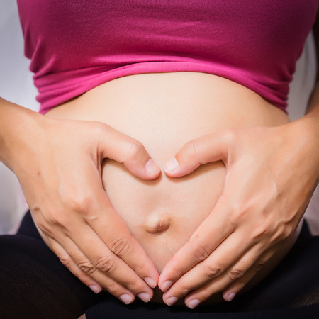Pregnant woman pregnancy concept heart on stomach. 