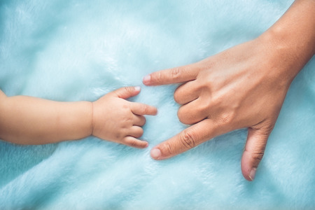 Baby and mothers hands made symbol of love.の写真素材