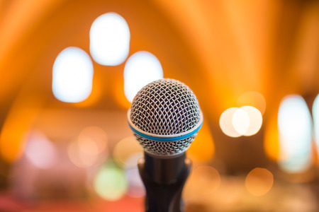Microphone in concert hall or conference room with defocused bokeh lights in background