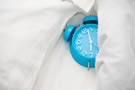 Blue alarm clock and bedの写真素材