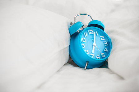 Blue alarm clock and bedの写真素材