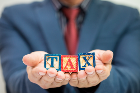 Tax Concept with wooden block in business hand,Businessの写真素材