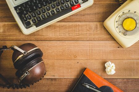 Top view of notebook on the wood table , typewriter, old telephone and earphone ,free spaceの写真素材