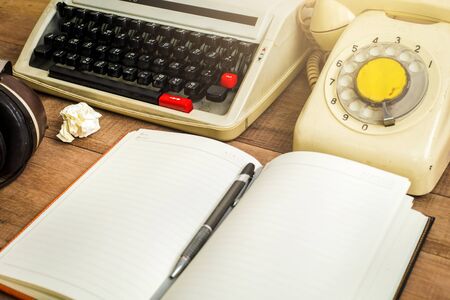 Top view of notebook on the wood table , typewriter, old telephone and earphoneの写真素材