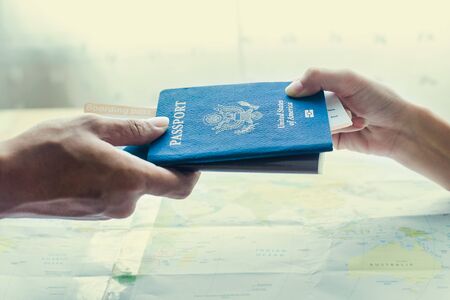 pretty travel agent giving tickets to client on map backgroundの写真素材
