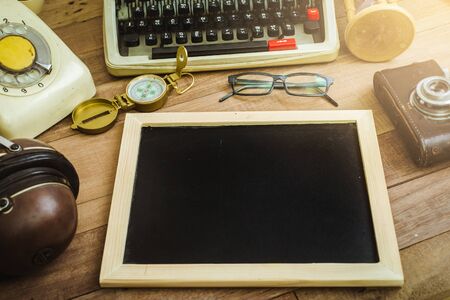 Top view of black board on the wood table , typewriter, old telephone and earphoneの写真素材