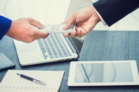 Business Hand giving money workspace in office- United States Dollars (or USD)の写真素材