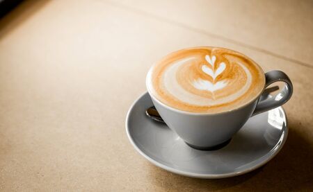 cup of coffee with heart pattern in a white cup on wooden backgroundの写真素材