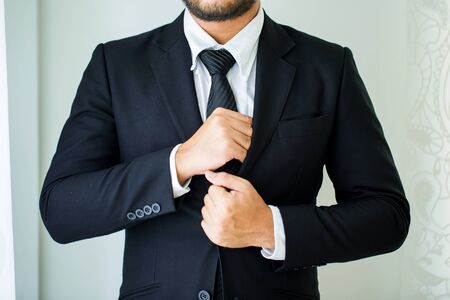 People, business,fashion and clothing concept - close up of man in shirt dressing up and adjusting tie on neck at home.の写真素材