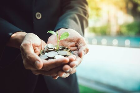 Business man holding little tree  growing on money,Money growing and saving with a man holding coinの写真素材
