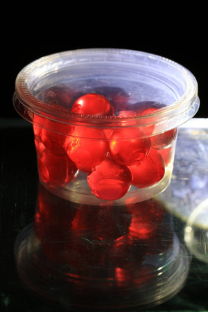 Close up transparency colorful jelly balls on small plastic cup on black background