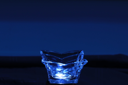 Close up glass cup in blue light on blue backgroundの写真素材