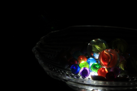 Close up transparency colorful marble in small glass tray on black backgroundの写真素材