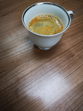 Close up bubbles of hot black coffee in white ceramic cup on wood tableの写真素材