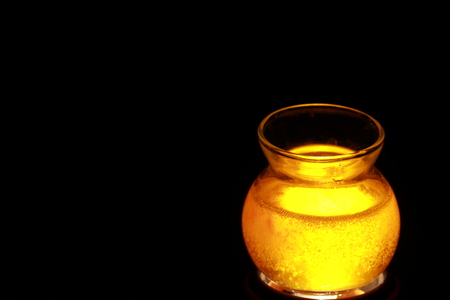 Side view of transparent honey bee in small glass cup on black backgroundの写真素材