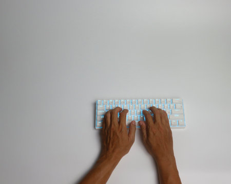 Hands typing on a computer keyboard on a white background. Top viewの写真素材
