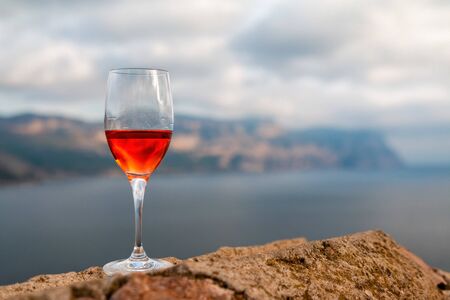 Glass of rose wine and with sea and beautiful seascape at sunset, close-up, horizontal composition. Summer evening relaxed mood conceptの写真素材