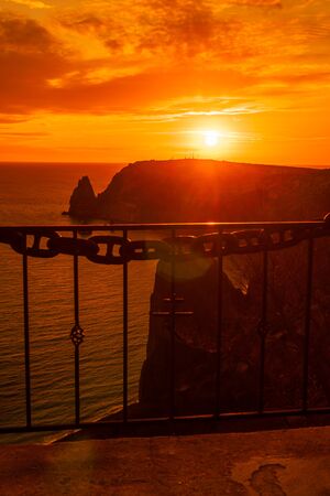 A red burning sunset with the silhouett of cape Fiolent and cliff over the seaの写真素材
