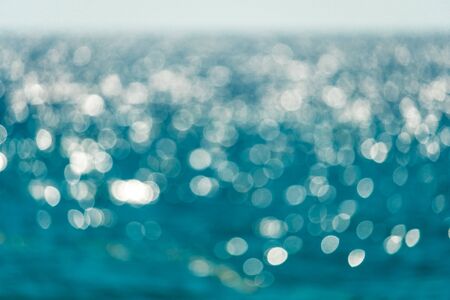 Abstract nature summer or spring ocean sea background. Small waves on water surface in motion blur with bokeh lights from sunrise.の写真素材