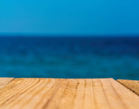 The blur blue sea background with wood floor foreground, relaxing outdoors vacation with paradise...