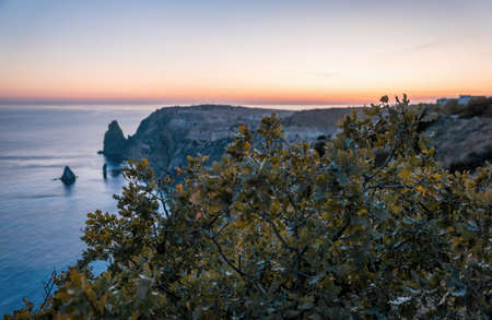 Autumn sea landscape with warm sunset light over rocky coastline. Calm sea on a background of rocky...