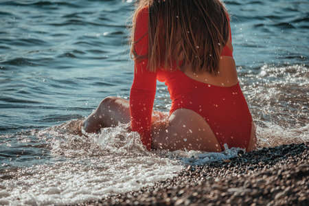 Young Caucasian female having fun in the waves of the sea which are splashing her on the coast. Vacation. Summertime. The concept of an travel, relax, active and healthy life in harmony with natureの写真素材