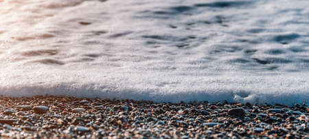 Selective focus. Sea foam on water surface in motion blur with bokeh lights from sunrise. Abstract nature summer ocean sunset sea background. Holiday, vacation and recreation background conceptの写真素材