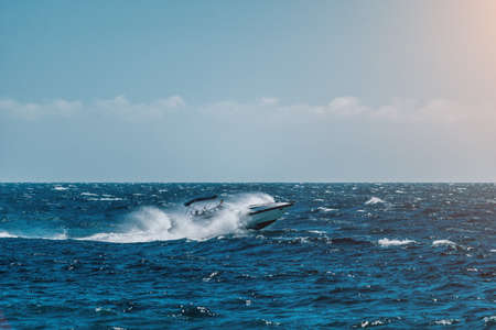 speedboat moving fast over wavy sea on a beautiful day white fast ship moving straight over blue water in background of blue sky.の写真素材