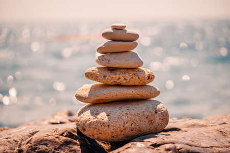 Pyramid stones on the seashore on a sunny day on the blue sea background. Happy holidays. Pebble...