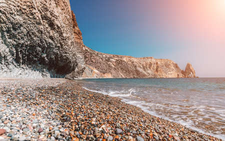 view of the sunset sea and the beach, the volcanic rock is lit by the warm sunset, sand and pebbles, volcanic basalt as in Iceland. Copy space. The concept of calmness, silence and unity with nature.の写真素材