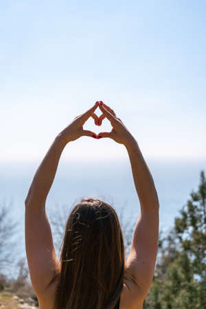 Young woman with long hair, fitness instructor in Sportswear Leggings and Tops, stretching before pilates, on a yoga mat near the sea on a sunny day, female fitness yoga routine conceptの写真素材