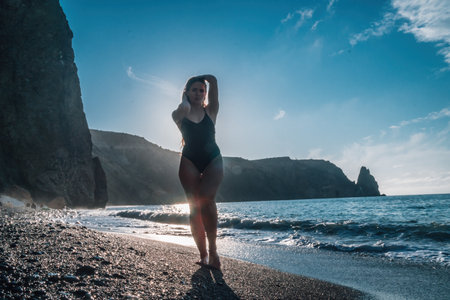 happy carefree sensual woman with long hair in black swimwear posing at sunset beach. silhouette of young beautiful playful positive woman outdoor. summer vacation and healthy lifestyle conceptの写真素材