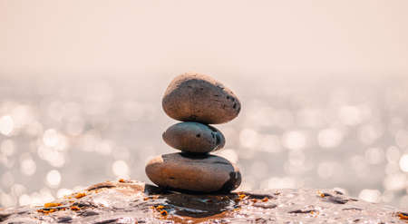 Pyramid stones on the seashore on a sunny day on the blue sea background. Happy holidays. Pebble beach, calm sea, travel destination. Concept of happy vacation on the sea, meditation, spa, calmness.の写真素材