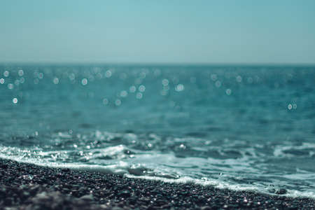 Abstract nature summer ocean sunset sea background. Small waves on water surface in motion blur with bokeh lights from sunrise. Holiday, vacation and recreational background conceptの写真素材