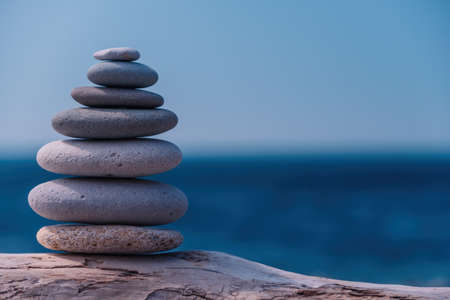 Pyramid stones on the seashore on a sunny day on the blue sea background. Happy holidays. Pebble beach, calm sea, travel destination. Concept of happy vacation on the sea, meditation, spa, calmness.の写真素材