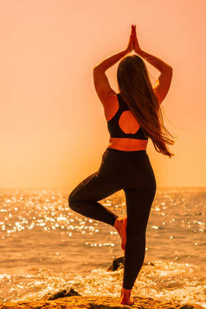 Young woman with long hair, fitness instructor in Sportswear Leggings and Tops, stretching before...