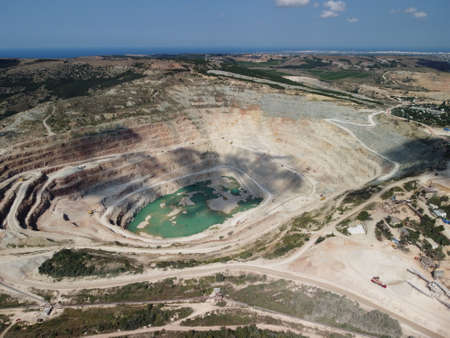 Aerial view industrial of opencast mining quarry with lots of machinery at work - extracting fluxes...