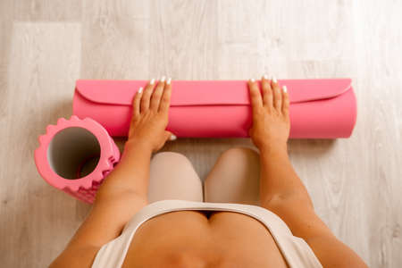 Young woman with long hair, fitness instructor in beige sportswear, preparing for stretching and...