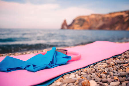 Magic pilates ring and rubber band on yoga mat near sea Female fitness yoga concept. Healthy lifestyle harmony and meditation.の写真素材